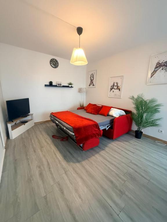 a bedroom with a red bed and a television at Les Trois koush in Courcouronnes