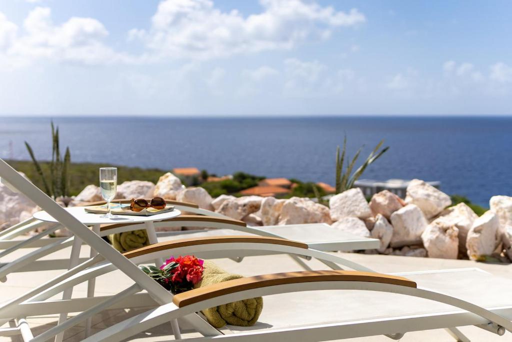 a table with a glass of wine and flowers on it at Villa Esmeraldas 1207 - Coral Estate in Willibrordus