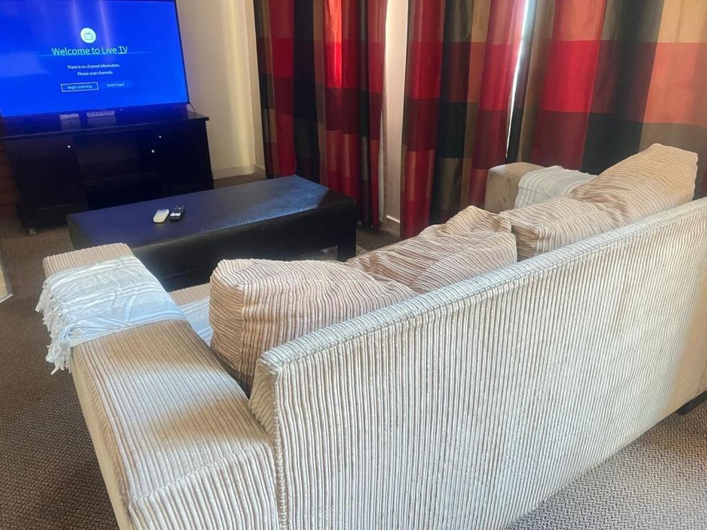 a living room with two white couches and a tv at Peaceful stays in Mapungubwe in Johannesburg
