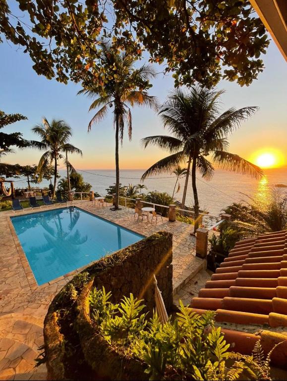 a swimming pool next to the beach at sunset at VELINN Pousada 8 Ilhas in Ilhabela