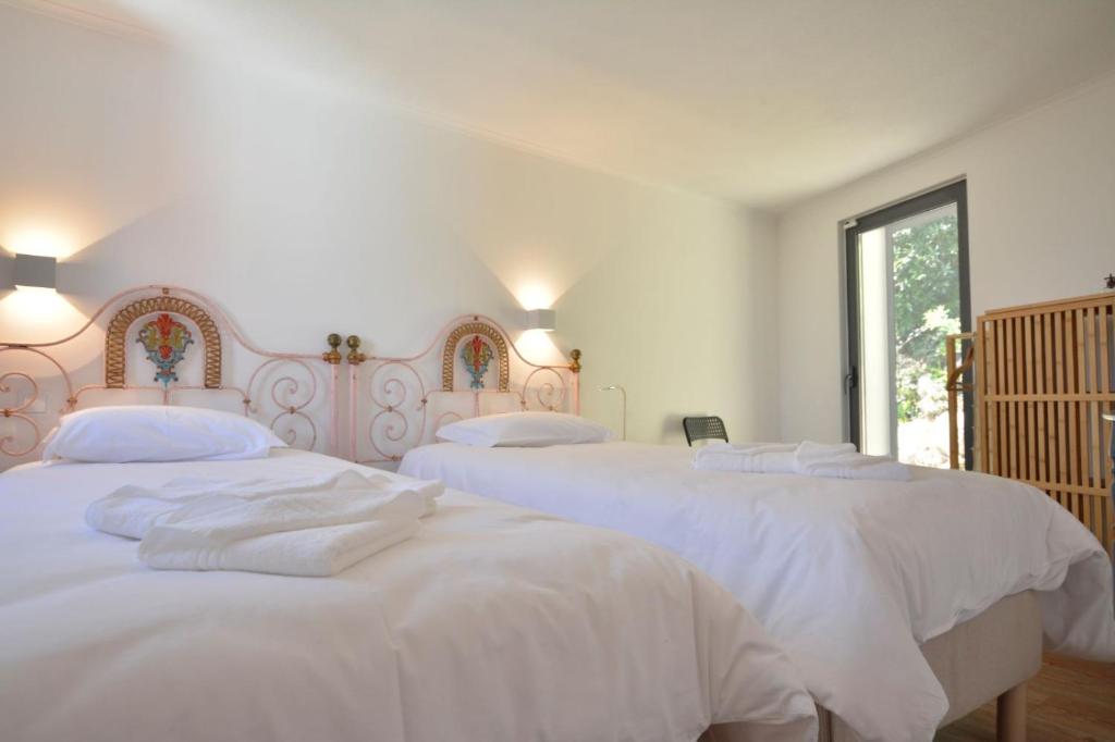 three white beds in a white bedroom with a window at Casinha in Sintra