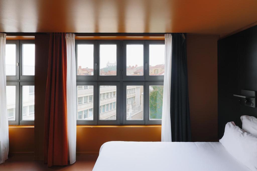 a bedroom with two beds and a large window at People Lyon Hotel in Lyon