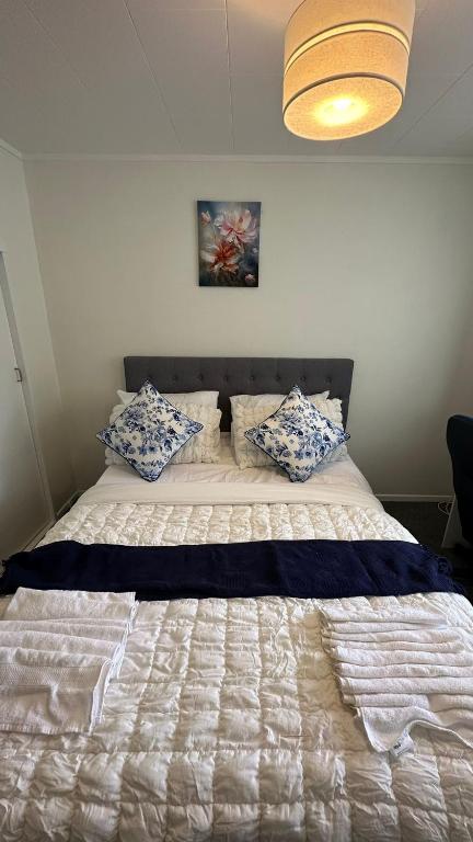 a bed with blue and white pillows in a bedroom at Sochi A double bed Room in a nice home in Upper Hutt