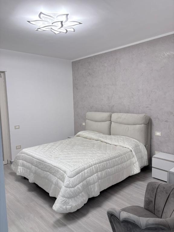 a white bedroom with a bed and a chair at Oltre Le Onde in Nova Siri Marina