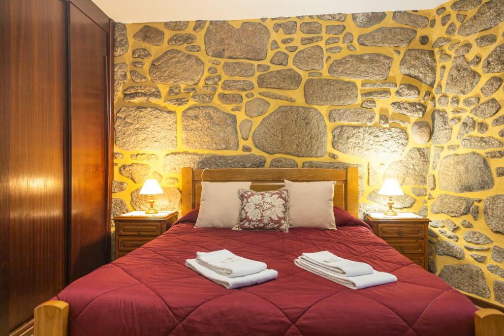 a bedroom with a red bed with two towels on it at Casa da Ramada in Campo do Gerês