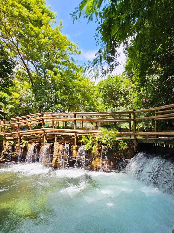 a wooden bridge over a waterfall next to a river at Thermas Paradise Residence in Rio Quente