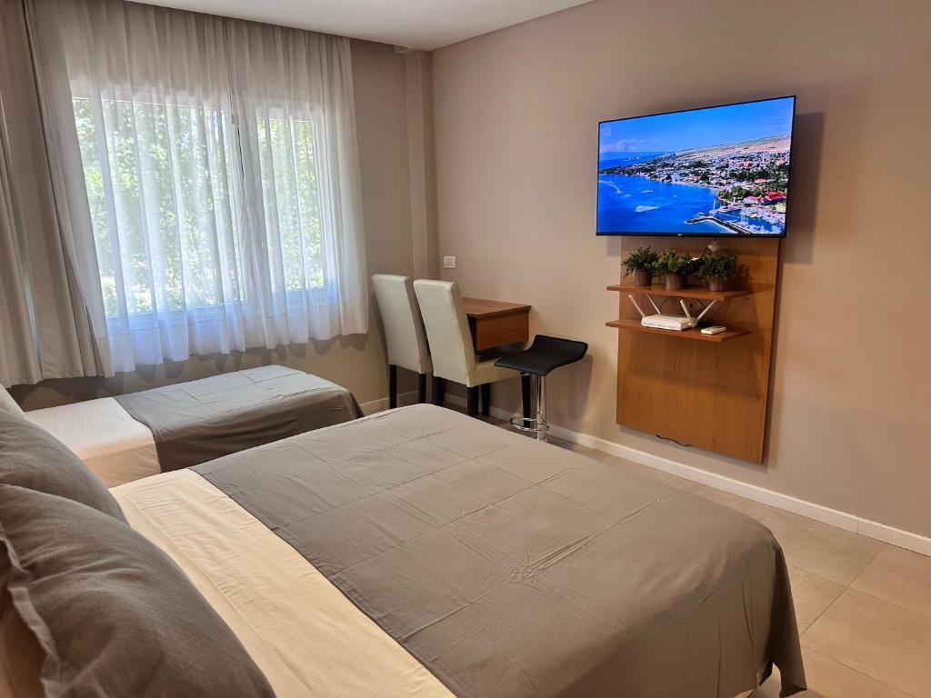 a hotel room with two beds and a flat screen tv at Suite Rincón del Sol 107 in Pinamar