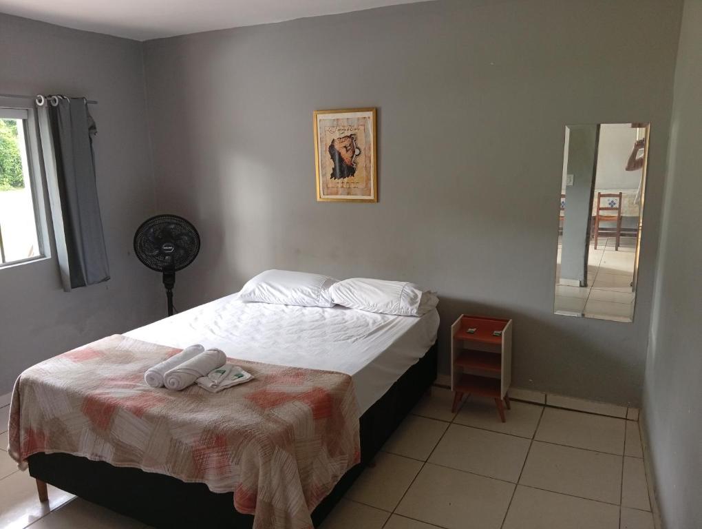 a small bedroom with a bed and a mirror at Hospedagem estação in Morretes