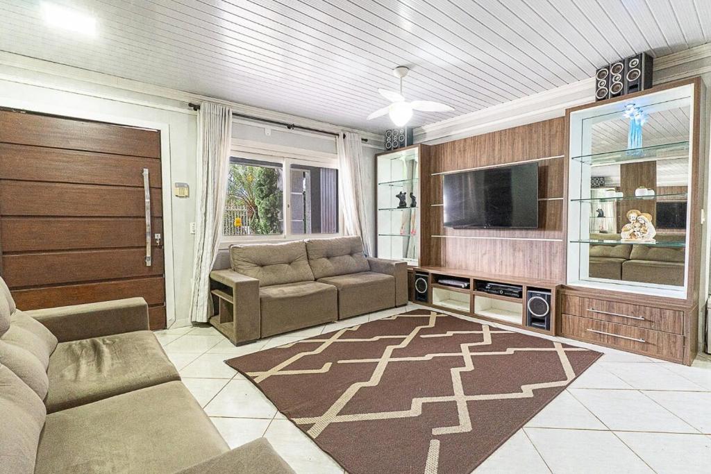 a living room with a couch and a tv at Casa Atlântida in Xangri-lá