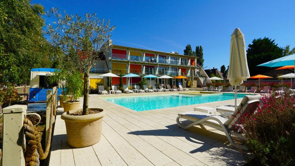 a pool with chairs and umbrellas next to a hotel at Colors Holiday Hotel in Siófok