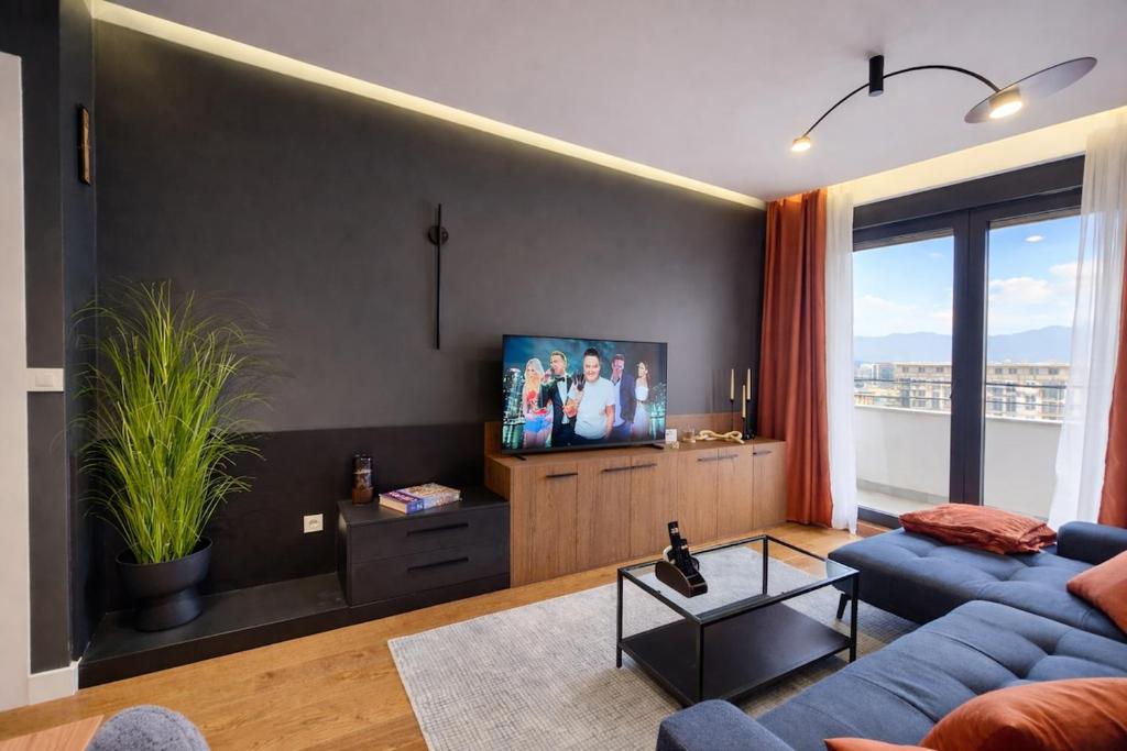a living room with a blue couch and a tv at Urban Forest Apartment - with free Garage in Podgorica