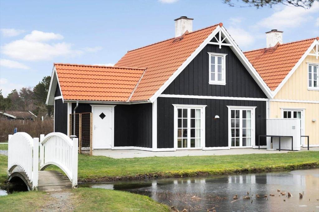 a black house with an orange roof next to a river at BV435-Blavand-Horns-Bjerge-3-59 in Blåvand