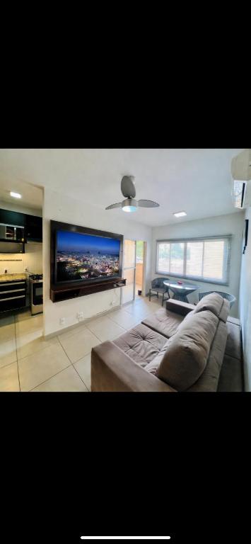a living room with a couch and a flat screen tv at Edifício Cristo Rei in Marília