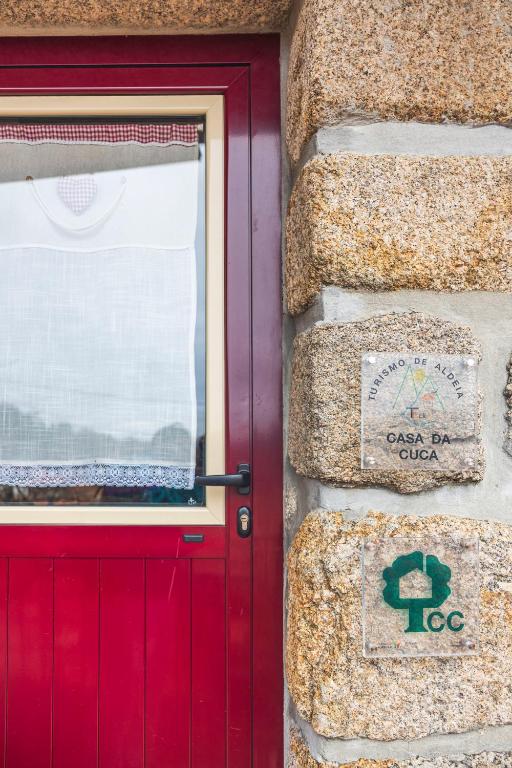 a red door on a stone wall with a sign on it at Casa da Cuca in Campo do Gerês