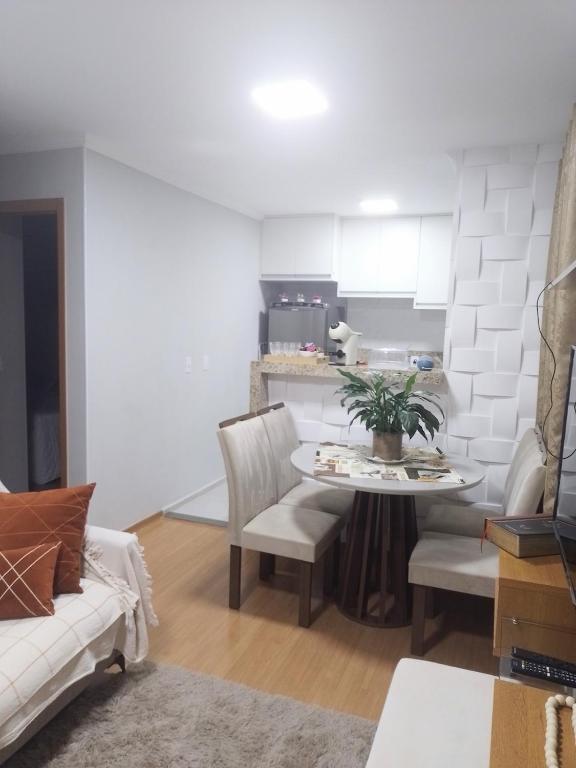 a living room with a table and chairs and a kitchen at Juhh Bella in Botucatu