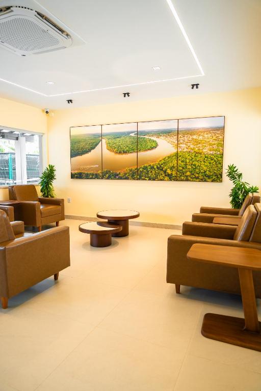 a lobby with couches and tables and a large painting at Hotel Equinócios Express in Barcarena