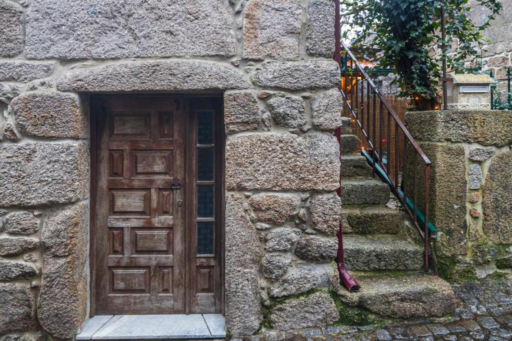 a stone building with a wooden door and stairs at Casa dos Cobertos in Terras de Bouro