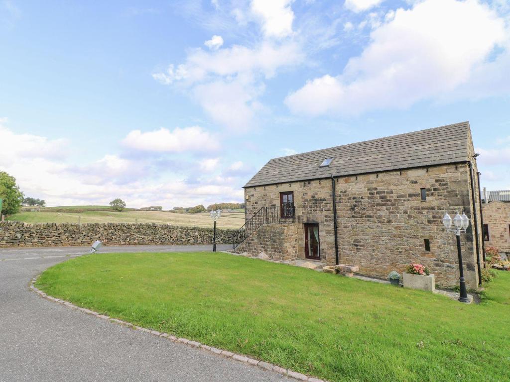 ein altes Steingebäude mit einem grasbewachsenen Hof neben einer Straße in der Unterkunft Riber View Barn in Chesterfield