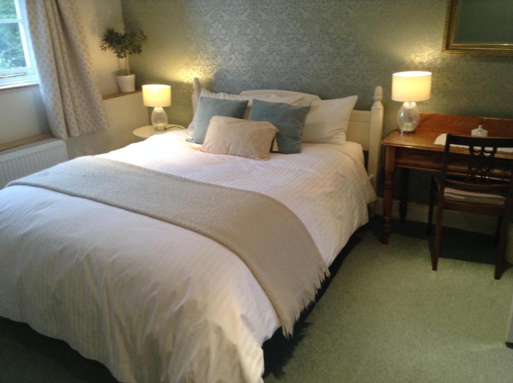 a bedroom with a large white bed with two lamps at Manor Farm in Poundon
