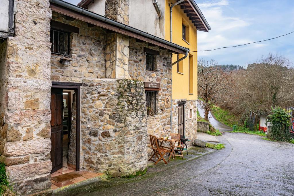 a stone building with a table and chairs outside at La Casina Del Fornu in Pravia