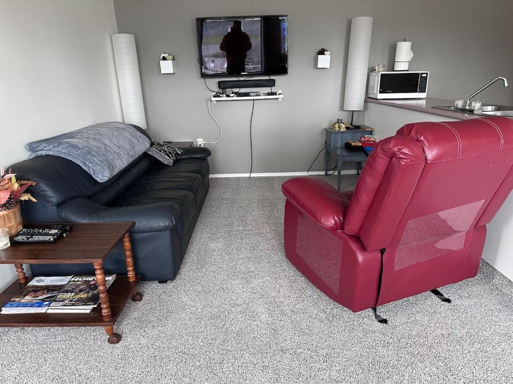 a living room with a couch and a red chair at Texada Hunter Hiker friendly suite in Vananda