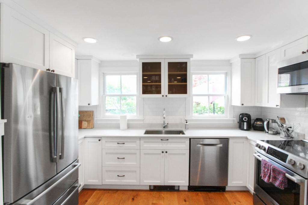 a kitchen with white cabinets and a stainless steel refrigerator at Harbor Breeze Townhouse in Provincetown