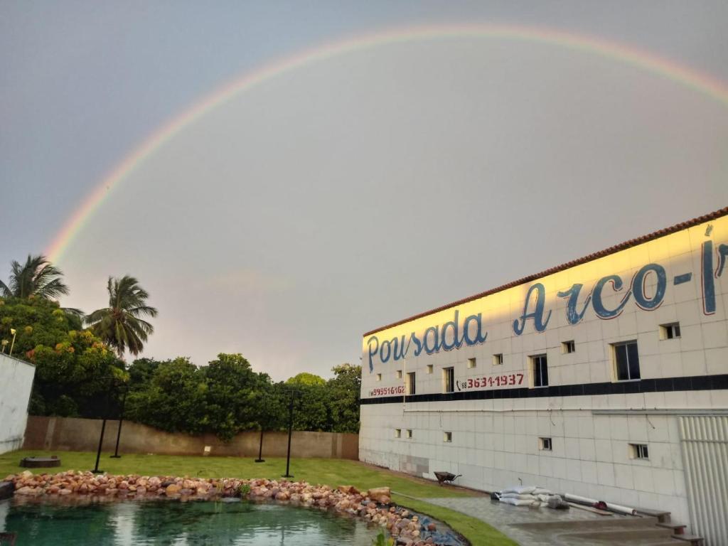 a rainbow over a building with a pool of water at Hotel Arco-Íris in Itapipoca