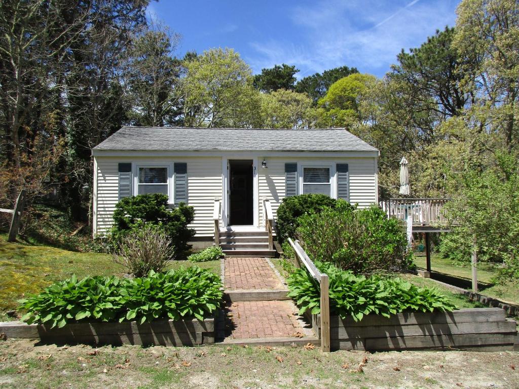 a small white house with a porch in a yard at Anchors Aweigh in Brewster