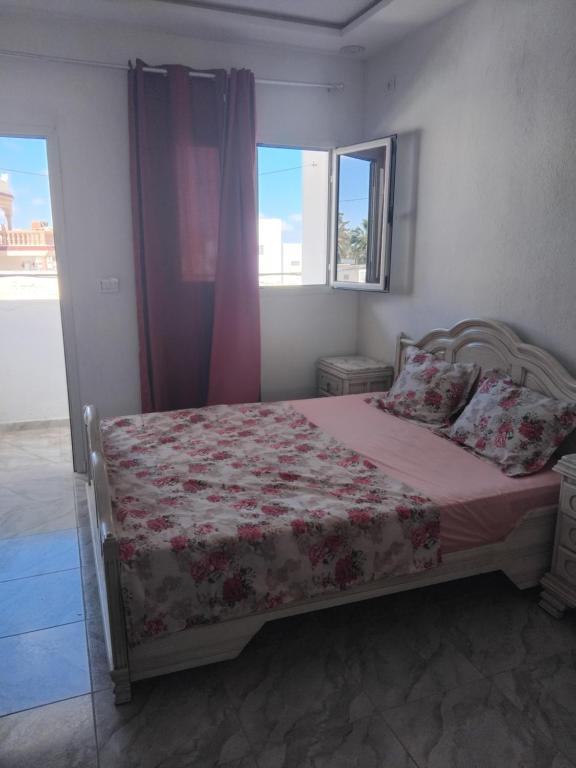 a bedroom with a bed with a pink blanket and a window at Appartement S1 Tulipe in Zarzis