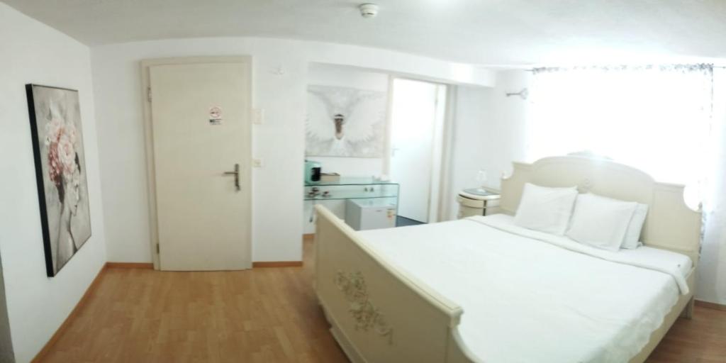 a white bedroom with a large white bed with white pillows at Zimmer perla in Chur