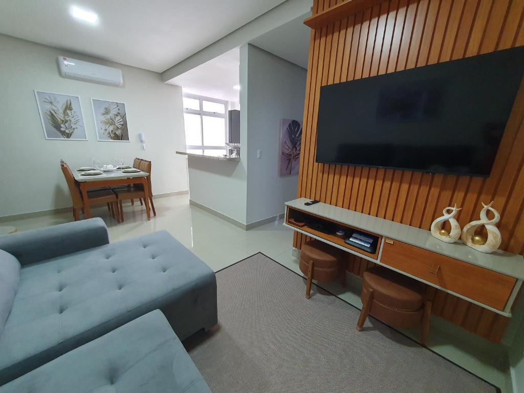 a living room with a couch and a large flat screen tv at Praia da Graciosa Apartamento 2 quartos in Palmas