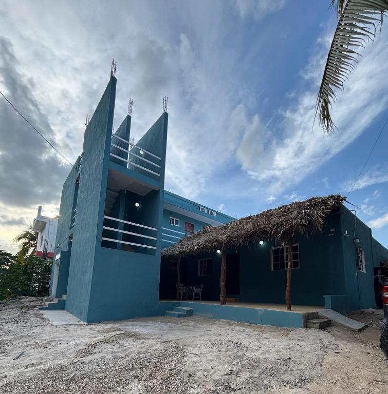 a blue building with a straw roof at Casa GLEZAR el cuyo in El Cuyo