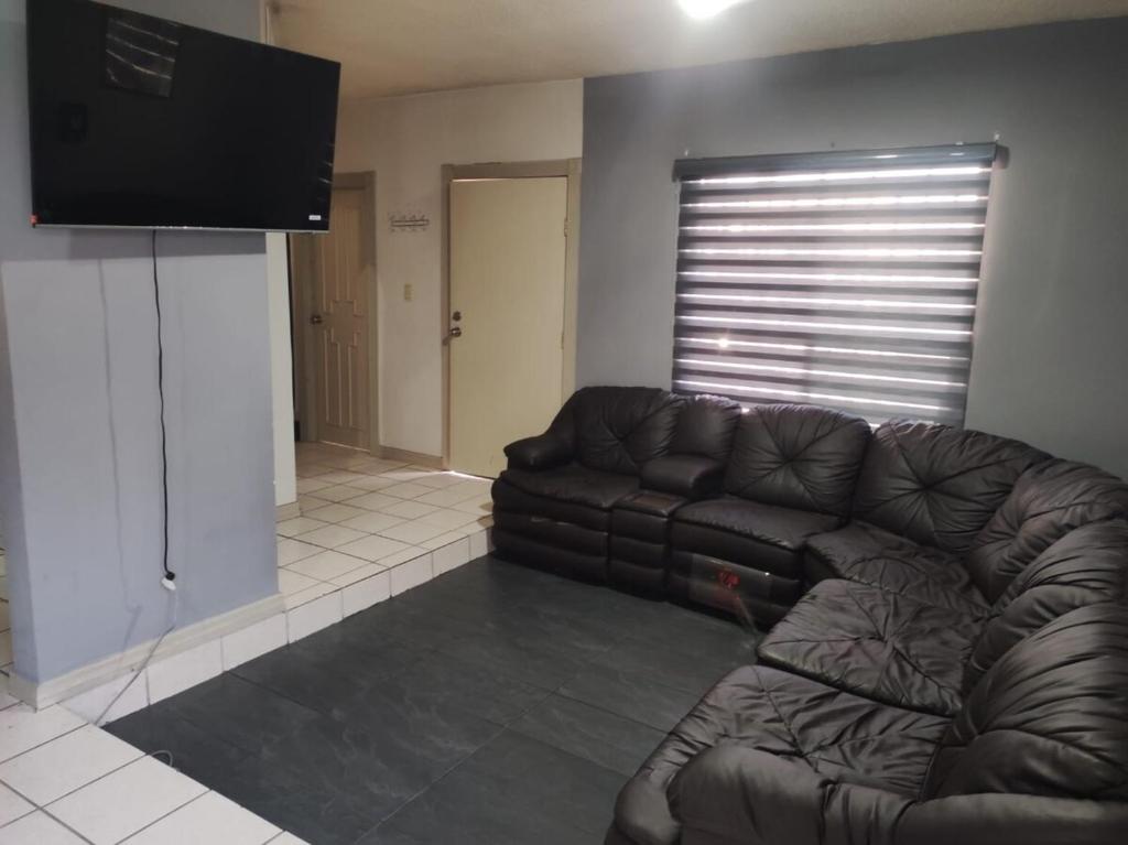 a living room with a leather couch and a flat screen tv at Floresta in Manuel F. Martínez