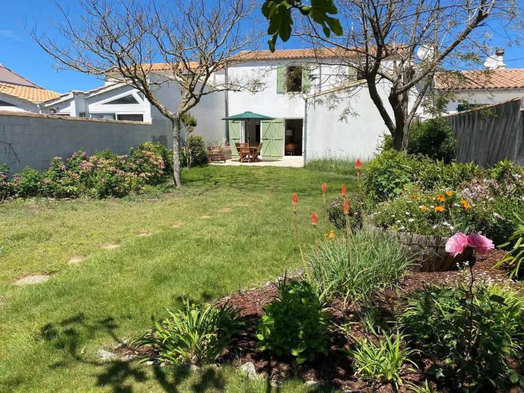 a home with a yard with flowers and a fence at La Villa de la Digue in Saint-Clément-des-Baleines