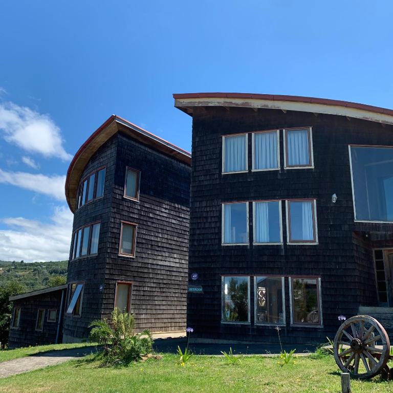 a black brick building with a wheel in front of it at Lodge Cumbres de Chiloe in Castro