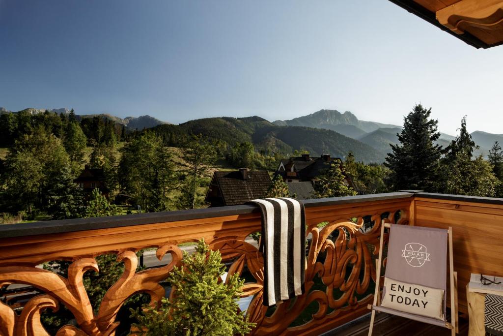 a balcony with a wooden railing with mountains in the background at Villa 11 Folk & Design in Zakopane