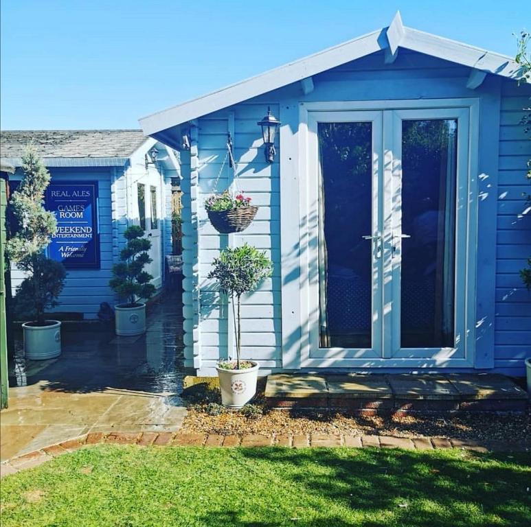 a blue house with a porch with potted plants at Weston's Wood Cabins in Blakeney