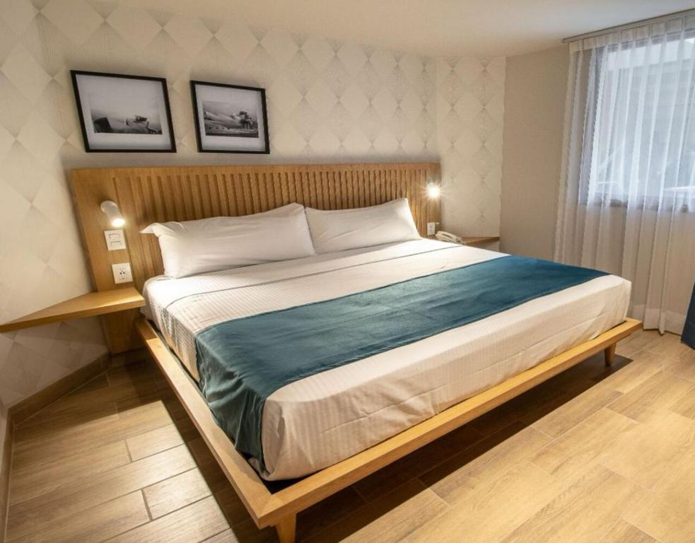 a bedroom with a large bed and two pictures on the wall at Oliva Plaza Hotel in Guadalajara