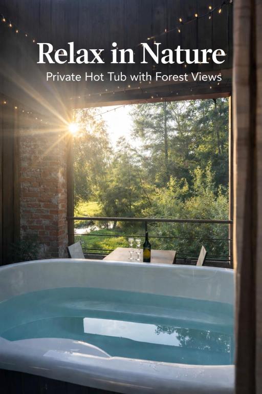 a bath tub with a view of the forest at La Filature 1813 in Wasselonne