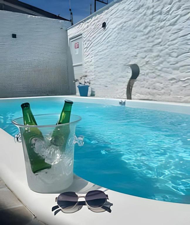 two bottles and glasses next to a swimming pool at Flats com Temática Grega na Praia de Aruana | Atena Flats in Aracaju