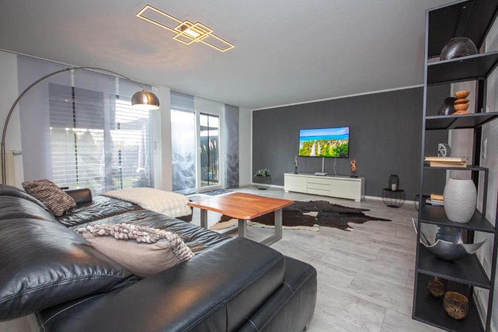a living room with a leather couch and a tv at Modern Luxury Villa Antonia in Mössingen