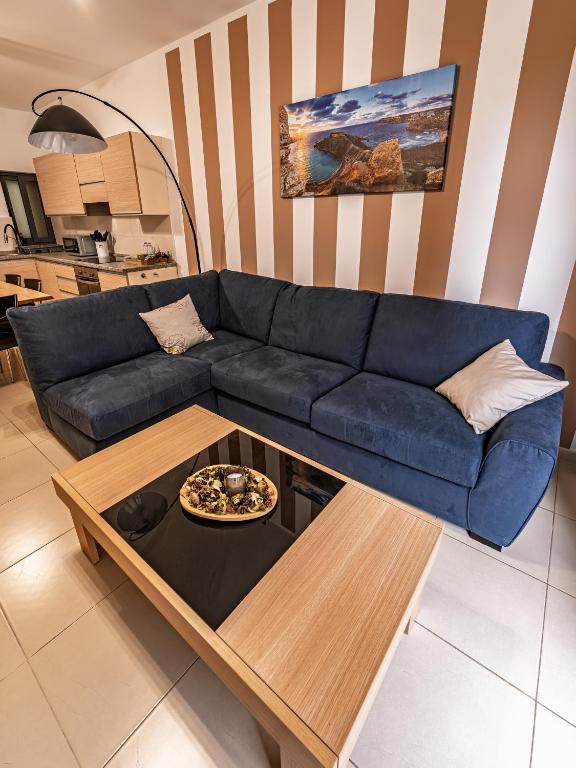 a living room with a blue couch and a table at Cobalt Canopy a Spacious 2 Bedroom Apartment in St. Paul's Bay