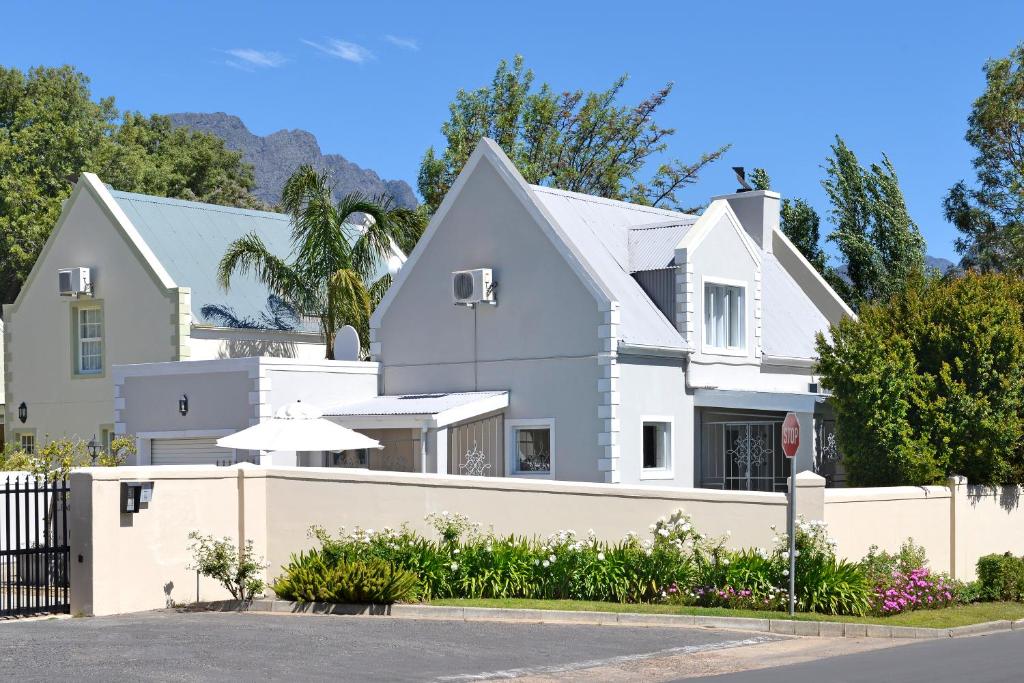 una casa blanca con una valla blanca en Lemon Tree Cottage Self Catering en Franschhoek