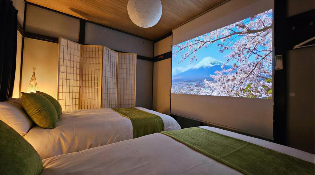 a room with two beds and a large tv on the wall at 紡ぎの宿 桜 - 民泊 - Tsumugi no Yado SAKURA in Abiko