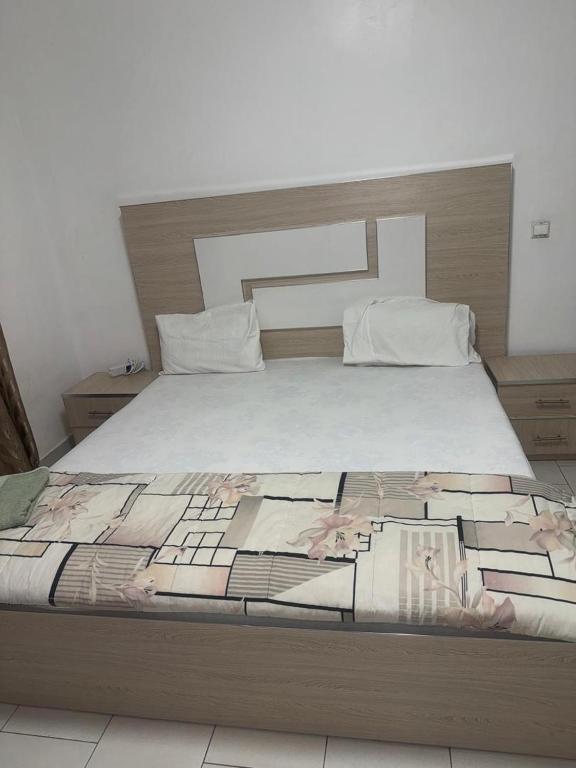 ein Schlafzimmer mit einem großen Bett und einer weißen Tagesdecke in der Unterkunft Résidence OUZA in Dakar