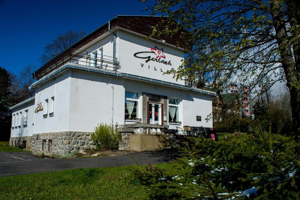 a white building with a sign on the side of it at Penzion Villa Gerlach in Nový Smokovec