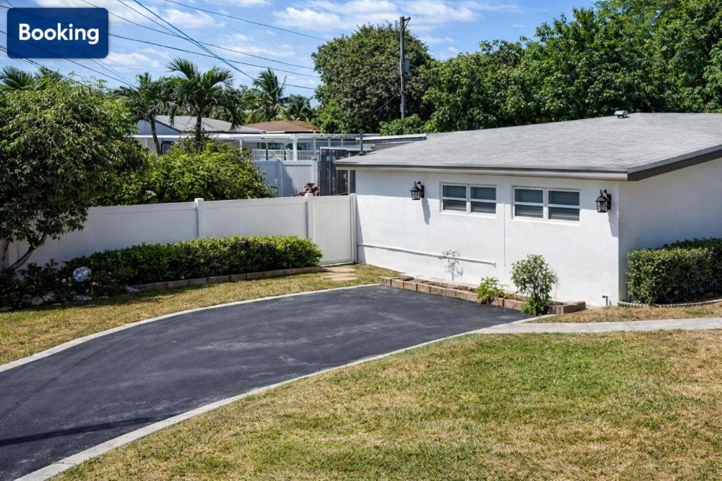 a house with a white fence and a driveway at Modern Hard Rock Apartment in Miramar
