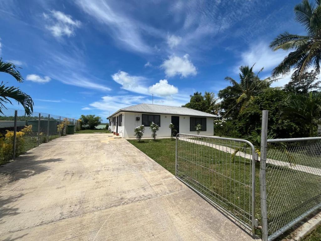a house with a fence next to a dirt road at Lagoon House in Veitongo