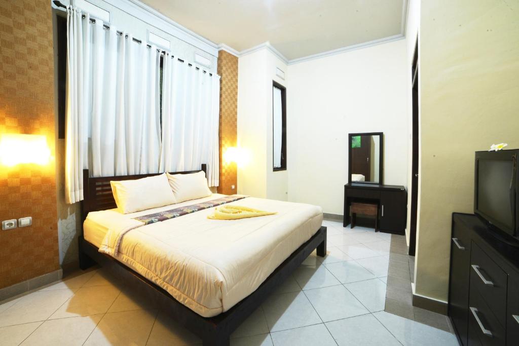 a bedroom with a large bed and a television at Ganggas Homestay in Jimbaran
