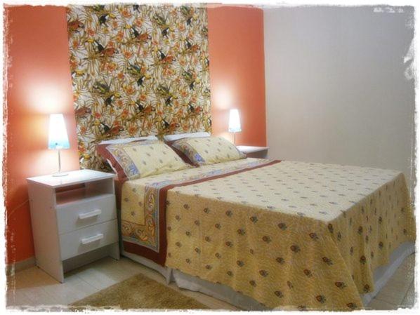 a bedroom with a bed and a painting on the wall at Apt. de Setiba - HOSPEDARIA OCA RUCA in Guarapari